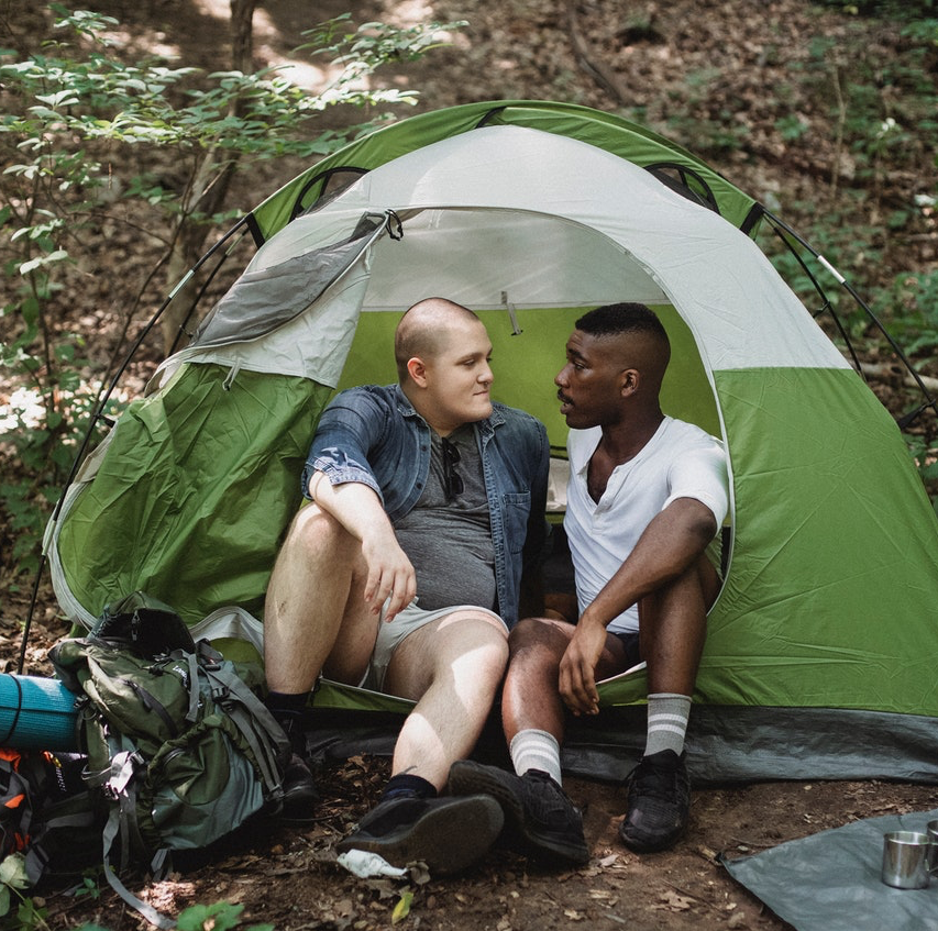 Zwei Menschen sitzen einander zugewandt in einem Zelt in der Natur
